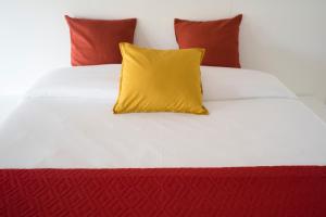 a yellow pillow on a white bed with red pillows at Relais Officina del Tempo in Paese
