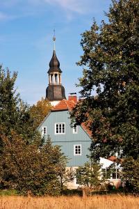 Charlottes Pfarrgarten في Niesky: كنيسة بيضاء فوقها برج