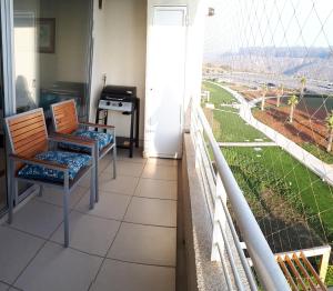 Una habitación con dos sillas y un balcón con vista. en Laguna Playa Privada, Vista al Mar, en Algarrobo