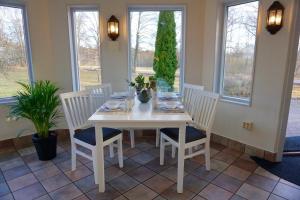 a white dining room table with four chairs and windows at Gylleby Vandrarhem in Sunne