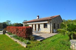ein kleines Steinhaus mit einer roten Hecke in der Unterkunft Sistak House in Rovinj