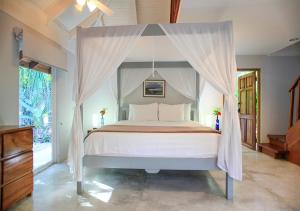 a bedroom with a canopy bed with white pillows at Casa Cecilia Beach Front in Santa Teresa Beach