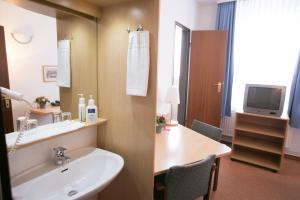 a bathroom with a sink and a mirror and a television at Rabes Hotel Kiel in Kiel +53 photos