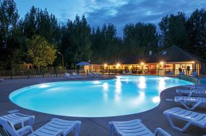 a large swimming pool with chairs and a building at Camping les Borgnes Saint-Sozy in Saint-Sozy