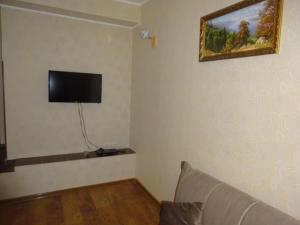 a living room with a couch and a flat screen tv on the wall at Старые Гагры-2 in Gagra