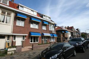 a car parked in front of a brick building with blue awnings at Hotel Duinzicht in Scheveningen