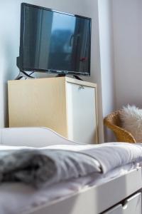 a tv sitting on top of a dresser with a cat laying on a bed at Sweet little Home in Essen