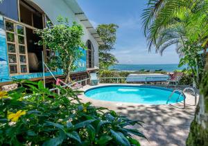 una piscina frente a una casa con el océano en Cabinas Arrecife, en Cahuita