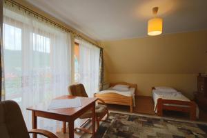 a room with two beds and a table and a window at Wynajem pokoi Natalia in Sromowce Niżne