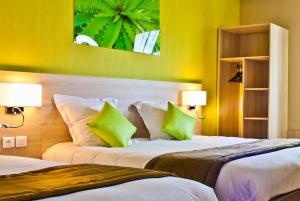 Una habitación de hotel con dos camas con almohadas verdes. en The Originals City, Hôtel des Lys, Dreux, en Dreux