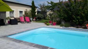 a blue swimming pool in a yard with pink chairs at la longère angevine in Juigné-sur-Loire