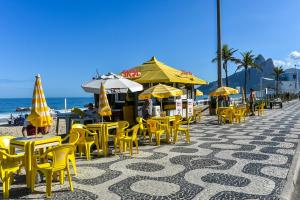 un grupo de sillas y sombrillas amarillas en una playa en Apartamento Ipanema Posto 9 com suite 2 quadras da praia, en Río de Janeiro