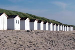 a row of buildings on a beach with a grassy hill at Fletcher Hotel - Restaurant de Cooghen in De Koog