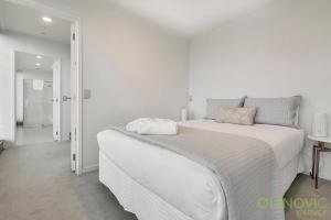 a white bed with two pillows on top of it at QV Stays Spacious City Getaway in Auckland