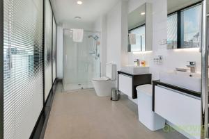 a white bathroom with two sinks and a toilet at QV Stays Spacious City Getaway in Auckland +7 photos