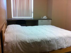 Cama blanca en habitación con ventana en Residence & Conference Centre - Sudbury North, en Sudbury