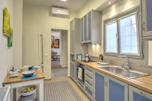 cocina con armarios azules, fregadero y ventana en Stylish and cozy house in Athens, Plaka en Atenas