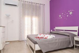 Schlafzimmer mit lila Wänden und einem Bett mit Kissen in der Unterkunft Appartamento Le Tre Rose in Trapani