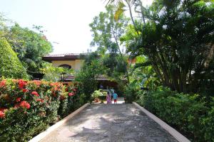 a group of people walking down a walkway in a garden at Villa del Sueño in Playa Hermosa