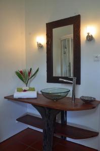 ein Badezimmer mit einem Waschbecken und einem Spiegel auf dem Tisch in der Unterkunft La Case Dentelle in Le Diamant