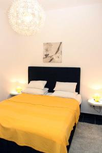 a bedroom with a yellow bed with two tables and a chandelier at Epicentar in Sarajevo