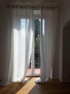 an open window with white curtains in a room at " Le cottage " in Mouans-Sartoux