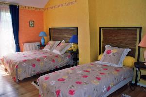 two beds in a bedroom with orange walls at le four au bois in Futeau