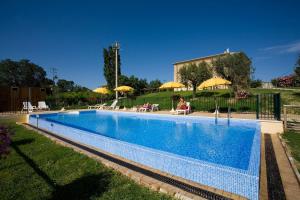 ein Pool mit Sonnenschirmen und Menschen, die um ihn herum sitzen in der Unterkunft Villa Montotto in Monterubbiano