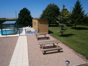 two wooden benches sitting next to a small wooden house at L'Escale de la Baie de Somme in Le Crotoy