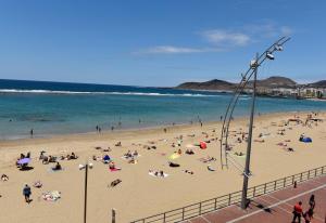 un grupo de personas en una playa con el océano en Apartamento Primera Línea Playa de Las Canteras, en Las Palmas de Gran Canaria