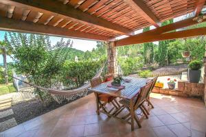 een patio met een hangmat en een tafel en stoelen bij Les Clèdes du Mazel in Banne