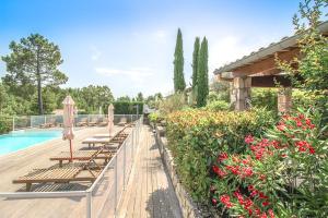 een rij banken naast een zwembad met bloemen bij Les Clèdes du Mazel in Banne