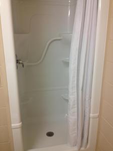 y baño con ducha con cortina blanca. en Residence & Conference Centre - Sudbury North en Sudbury