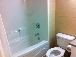 y baño con aseo blanco y ducha. en Residence & Conference Centre - Sudbury North, en Sudbury