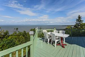 una terraza con mesa, sillas y el océano en Auberge de L'Anse, en Rivière-du-Loup