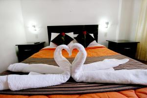 Dos cisnes haciendo un corazón en una cama en Hotel Peru Real, en Cusco