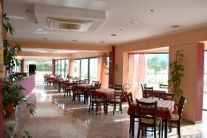 a dining room with tables and chairs and windows at Kalias Hotel in Vasiliki
