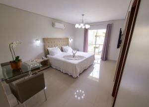 a bedroom with a bed and a table and a window at Marruá Hotel in Bonito