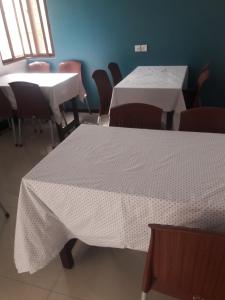 a room with two tables and chairs with white table cloth at Patel Residency Guest House in Karachi