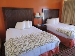 Cette chambre d'hôtel comprend 2 lits avec des draps blancs. dans l'établissement Royal Crest Motel, à Medford