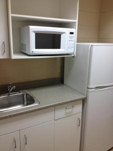 a kitchen with a white refrigerator and a microwave at Residence & Conference Centre - Sudbury North in Sudbury