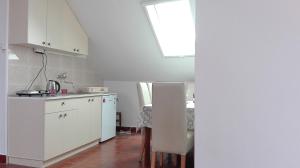 eine Küche mit weißen Schränken und einem Tisch in der Unterkunft Apartment Dixy in Belgrad