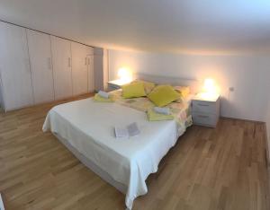 a bedroom with a white bed with yellow pillows at Apartmani Žužić in Krk
