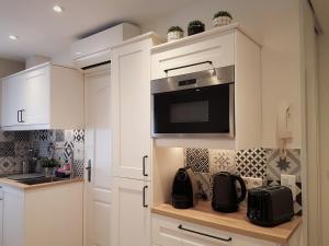 a kitchen with white cabinets and a microwave at La Bastido in Arles