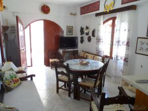 a living room with a table and chairs and a television at Liolio's Manor in Agalianós