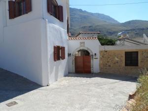 a white building with a red door with mountains in the background at Liolio's Manor in Agalianós
