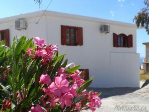 a white house with red windows and pink flowers at Liolio's Manor in Agalianós +7 photos