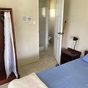 a bedroom with a bed and a bathroom with a toilet at Garden Bungalow in Sauteurs +13 photos