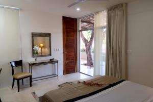 a bedroom with a bed and a desk and a window at Hotel Casa de Campo Conkal Merida in Conkal
