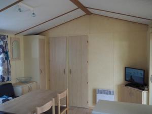 sala de estar con mesa y TV. en Camping La Prévoté, en Saint-Hilaire-de-Riez